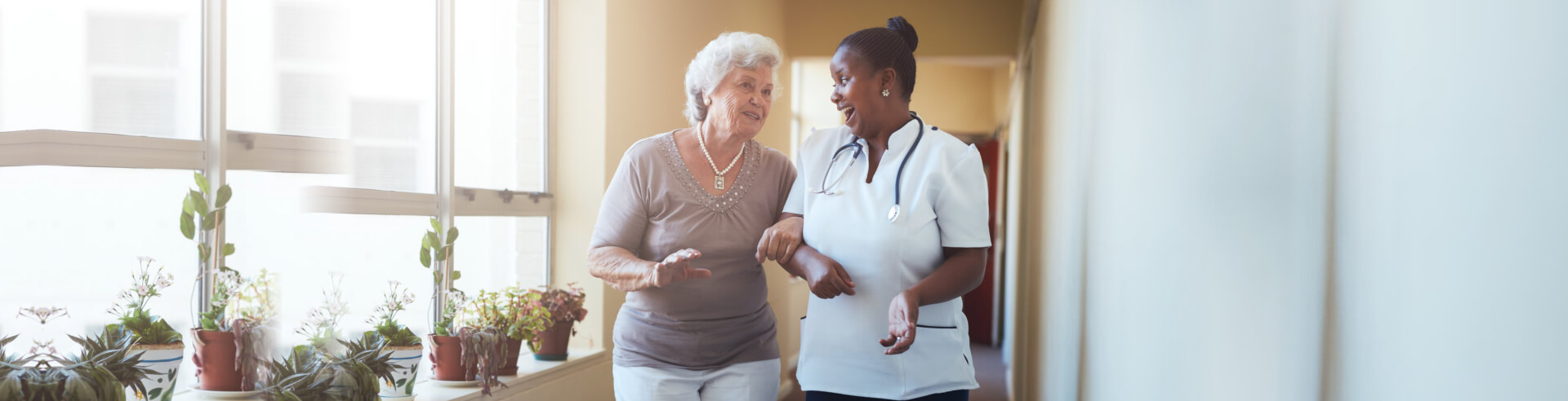 caregiver assisting senior woman in walking