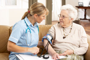 caregiver checking blood pressure of the old woman